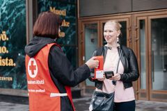 Alt-teksti: Nälkäpäivän lipaskerääjä ojentaa lippaan ohikulkijalle kadulla.