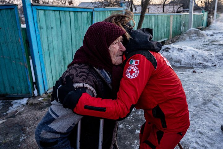 En äldre kvinna i Ukraina kramas av en person i en röd uniform från Italienska Röda Korset.