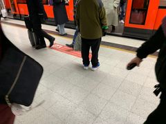 Ihmisiä tulossa ja menossa metroon Rautatientorin asemalla. Lattiatarrassa lukee "päästä poistujat ensin ulos".