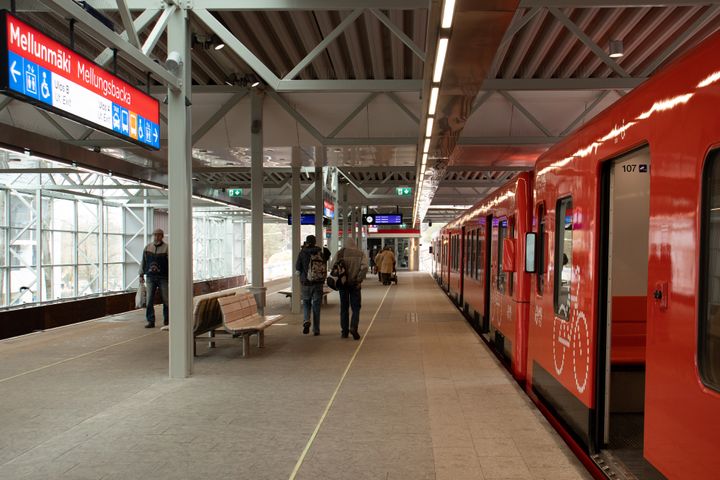 Mellunmäen metroasemalla metrojuna ja laiturilla matkustajia.