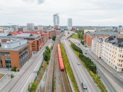 Metrorata ja metrojuna kuvattuna yläviistosta, Kalasataman metroasema näkyy taustalla.