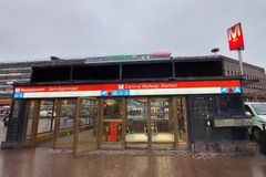 Pääsisäänkäynti Rautatientorin metroasemalle Asema-aukiolla, taustalla rakennuksia.