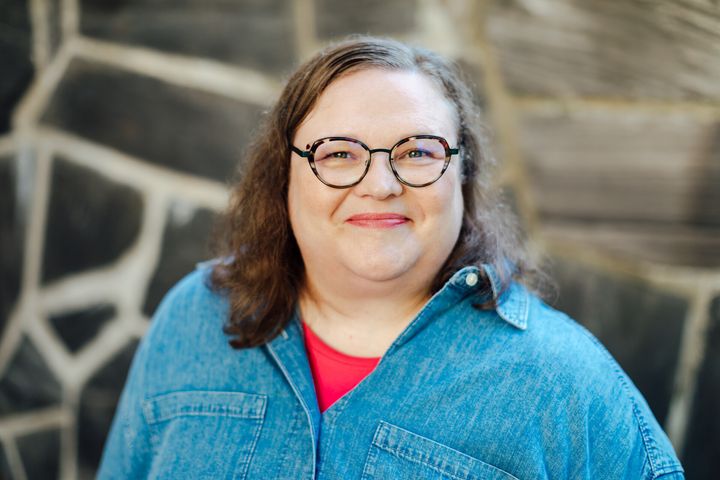 Kuvassa nainen katsoo kameraan ja hymyilee.