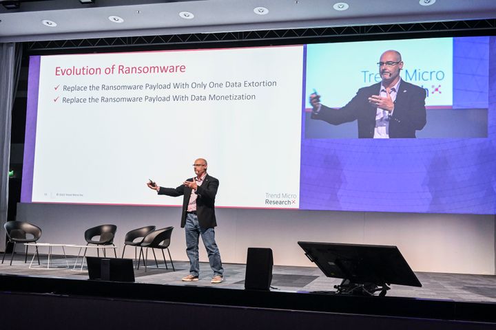 A person giving a presentation on the evolution of ransomware, standing on stage with a slide in the background.