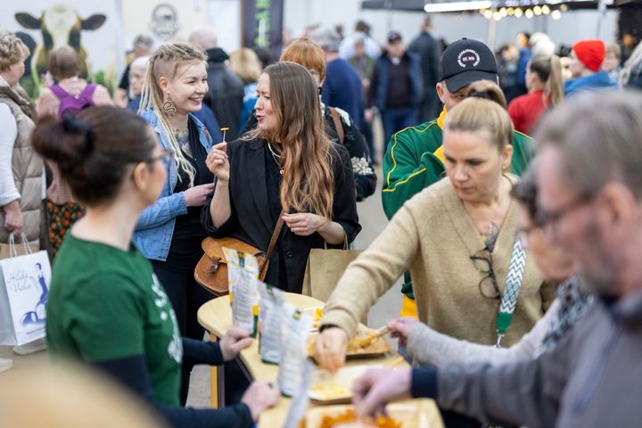 Alt-teksti: Ihmisiä maistelemassa tuotteita Lähiruoka & luomu -messuilla Helsingin Messukeskuksessa.