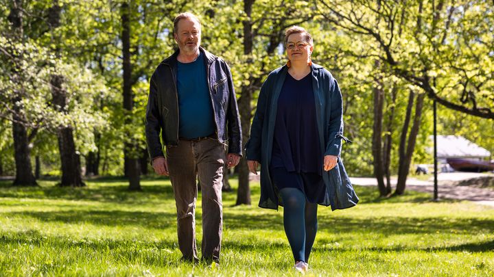 Mies ja nainen kävelevät vehreässä puistossa