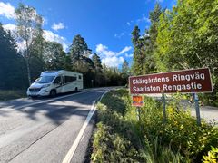 Saariston rengastie -kyltti maantien varressa ja vastaan tuleva matkailuauto.