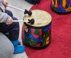 Lapsi soittamassa rumpua, lähikuva.