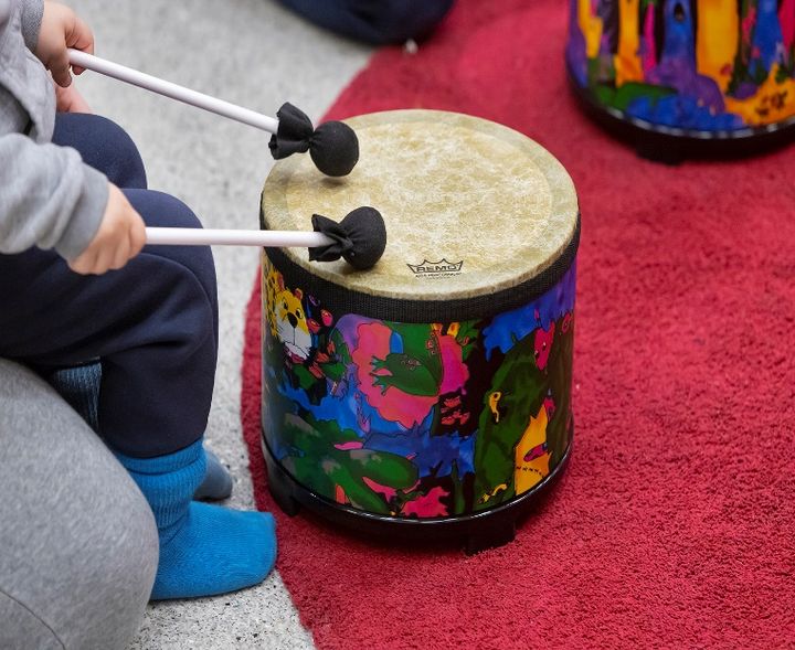 Lapsi soittamassa rumpua, lähikuva.