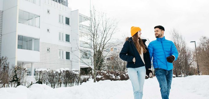 Kaksi henkilöä kävelee talvisella kadulla.