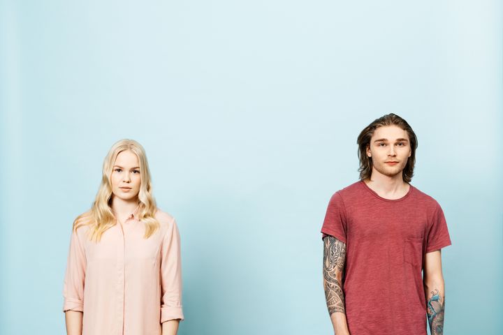 Kaksi nuorta, nainen ja mies, katsovat kameraan totisina.