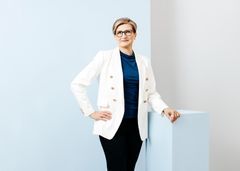 Vaaleaihoinen nainen valkoinen bleiseri päällään.