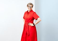 Punaisessa mekossa oleva nainen hymyilee.