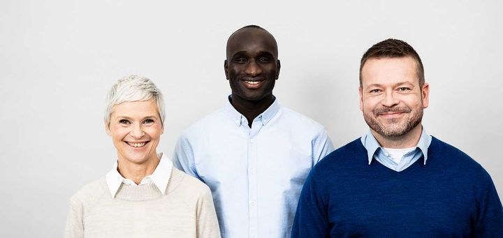 Kolme henkilöä rinnakkain hymyilemässä.