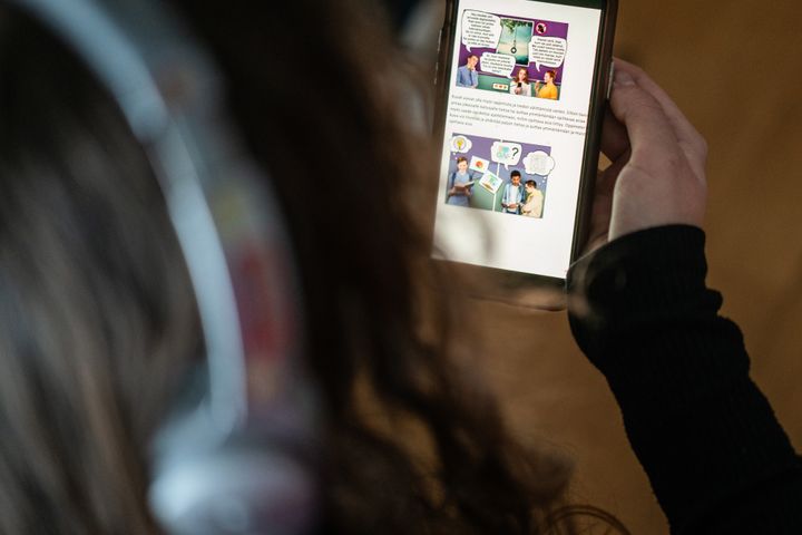 En person håller en mobil med en app för digital rehabilitering.