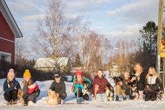 Ryhmä lapsia ja nuoria ulkona talvimaisemassa koirien kanssa.