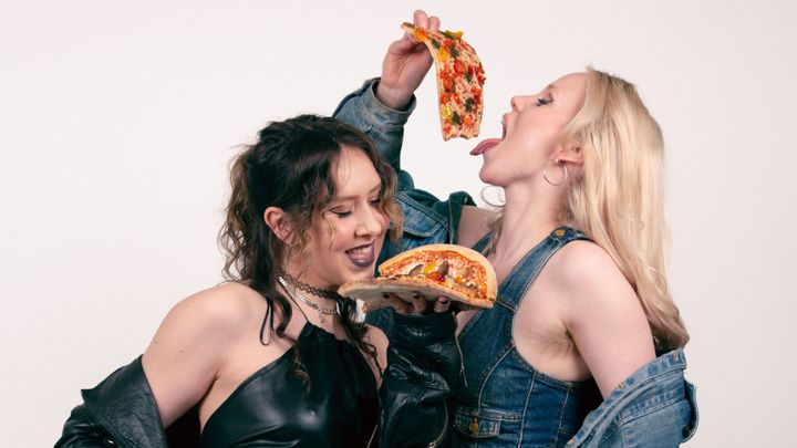 Kaksi henkilöä syö pizzaa.