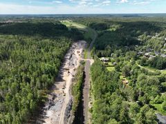 Ilmakuvassa näkyy junaraiteet, raiteiden vieressä oleva rakennustyömaa, puita ja pientaloja.