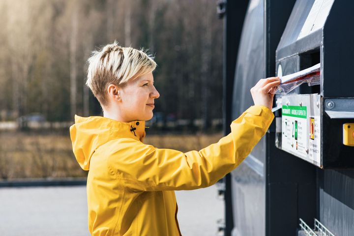 Henkilö laittaa muovipakkauksen kierrätysastiaan ekopisteellä.