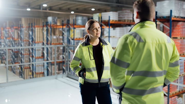 Kaksi henkilöä keskustelee yrityksen varastolla.