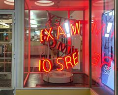 Storefront with red neon letters in disarray, creating a chaotic display.