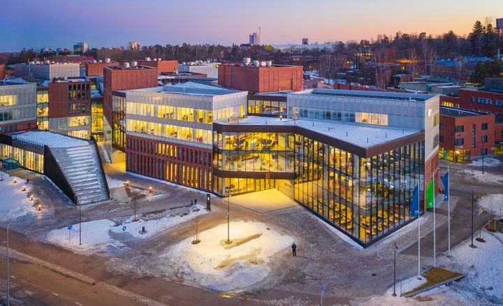 Ilmakuva modernista kampusrakennuksesta talvella iltahämärässä.