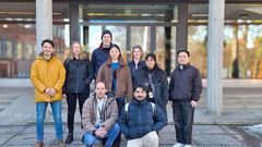 Kymmenen ihmisen ryhmä seisoo ulkona rakennuksen edessä.