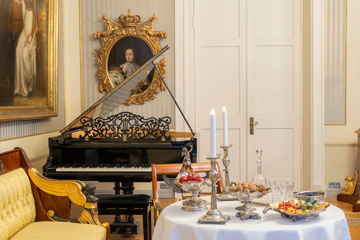 Jouluteemainen kattaus kotimuseossa, taustalla piano ja maalauksia.