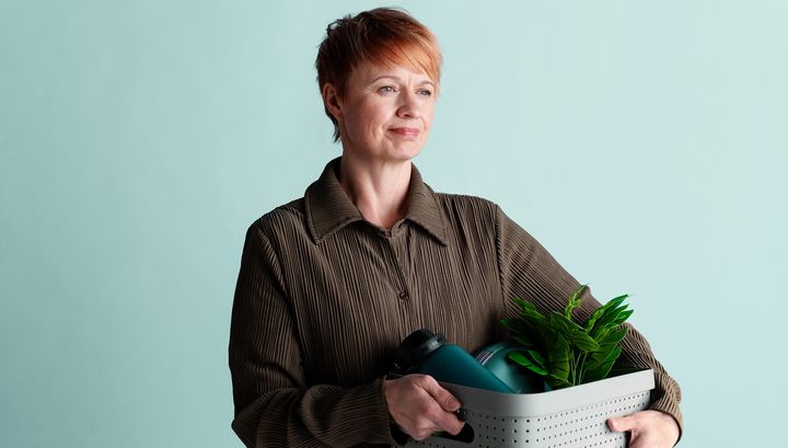 Henkilö pitelee kasvia sisältävää säilytyskoria vaaleansinisellä taustalla.