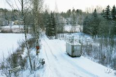 Harmaa mittausasema seisoo tien varressa.