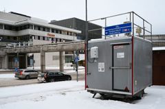 Harmaa mittausasema seisoo kadun varressa.