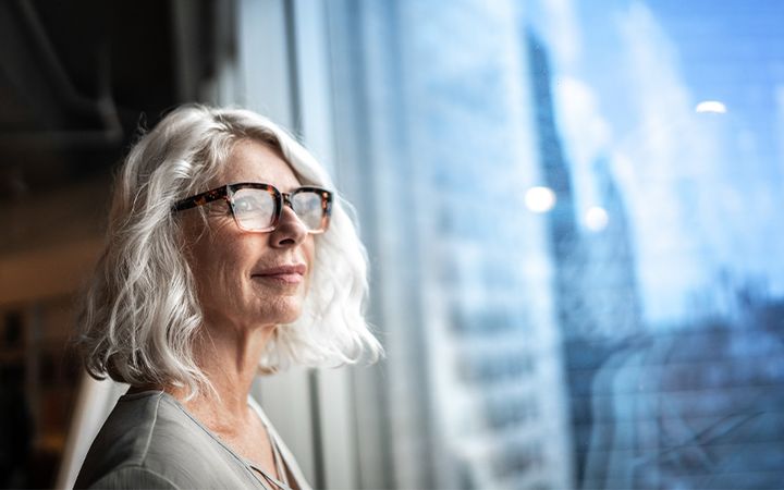 Keski-ikäinen nainen katsoo ulos ikkunasta