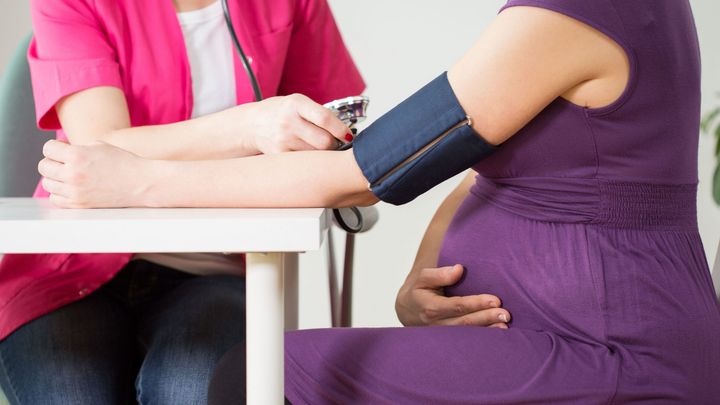 Hoitaja mittaa verenpainetta raskaana olevalta henkilöltä.