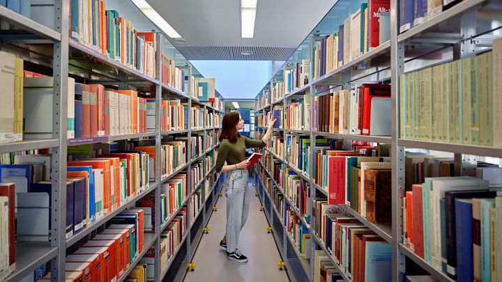 Nainen katsomassa kirjoja Oulun yliopiston kirjastossa Linnanmaan kampuksella.