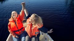 kaksi nuorta naista iloitsevat veneessä pelastusliivit päällä