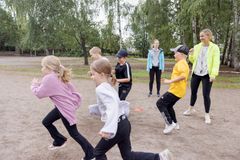 Barn leker utomhus på en grusplan tillsammans med en vuxen.