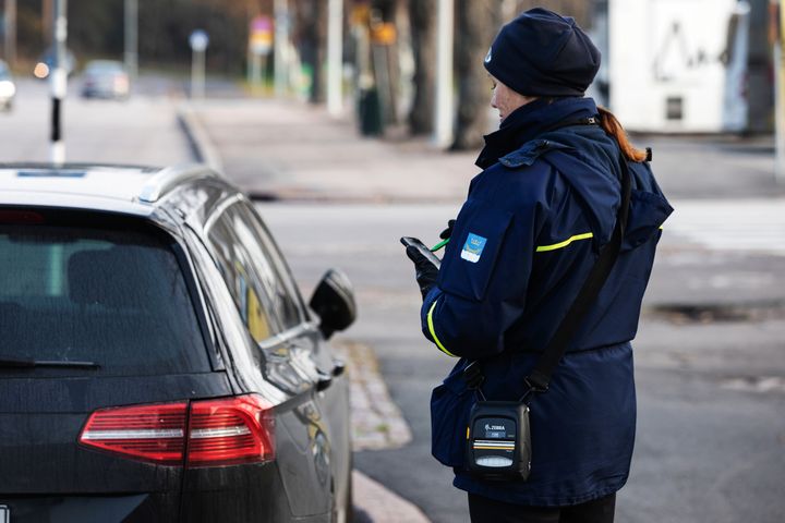 Pysäköinninvalvoja tarkastaa pysäköityä autoa.