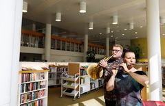 A man plays the trumpet and a woman plays the flute in Töölö Library.