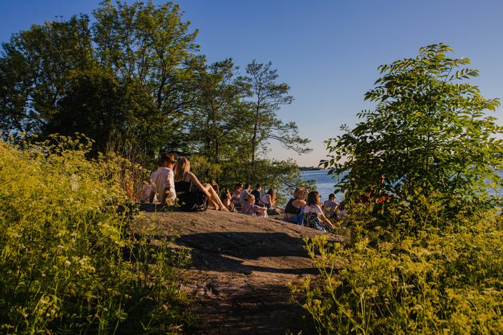 Ihmisiä istuskelemassa kalliolla kesäisessä säässä