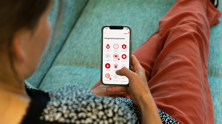 Henkilö selaa Verenluovuttajan sovellusta, jossa näkyvät virtuaaliset hengenpelastajamerkit.