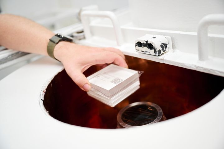 A person places environmental samples into a radiation measurement device in a laboratory.