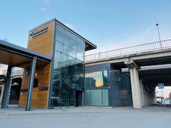 Entré till en modern tågstation med glas- och träpaneler.