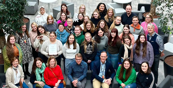 A group of smiling Erasmus+ BIP participants posing for a photo in an indoor setting at VAMK's Alere.