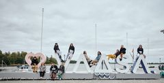 Group of VAMK's students sitting on large letter sculptures spelling 'VAASA' by a waterfront.