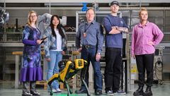 Agroup of five people stand together in Technobothnia teachning and research laboratory with a robot dog by their side.