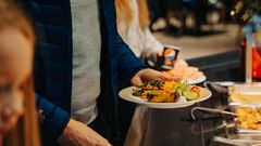 Henkilö ottaa ruokaa buffetpöydästä lautaselle.