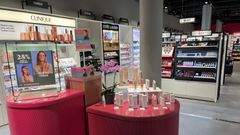 Kosmetiikkamyymälän sisätila, jossa näkyvissä eri meikkibrändien tuotetelineitä ja mainoksia.