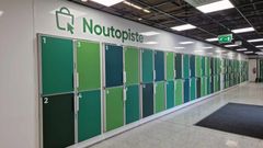 Vihreä-valkoiset noutolokerot järjestettyinä rivissä seinän vieressä, päällä kyltti, jossa lukee "Noutopiste".