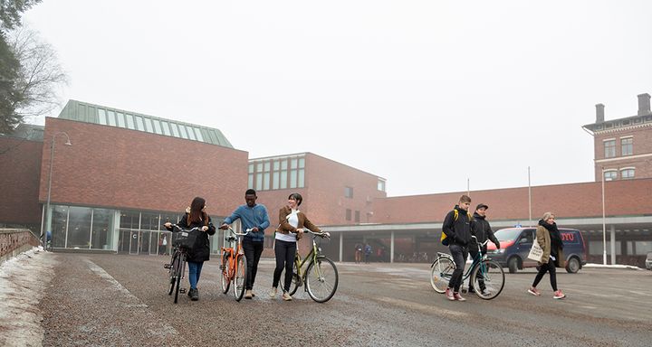 Opiskelijoita kävelemässä polkupyörien kanssa Jyväskylän yliopiston kampuksella.