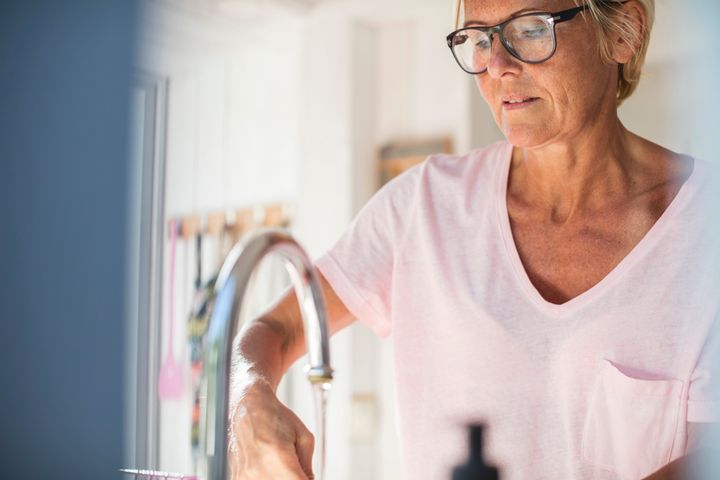 Nainen tiskaa astioita keittiössä.